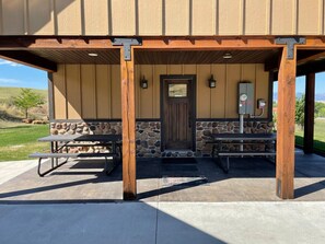 A building with a stone facade, wooden beams, a door, and a picnic table.
