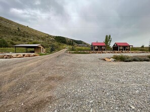 Un camino de grava que lleva a una zona rural con dos pequeñas construcciones de tejados rojos.