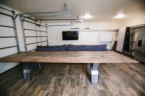 Una cocina moderna con una amplia mesa de madera, electrodomésticos integrados y un sofá gris.