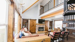 Een ruime woonkamer met een open haard, houten meubels en een balkon.