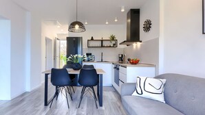 Una cocina moderna con comedor, que incluye una isla central, sillas negras y un sofá gris con un cojín decorativo.