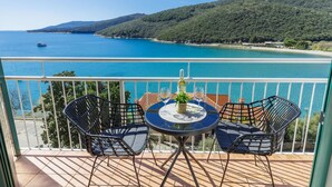 Un balcón con mesa y sillas que ofrece vistas a la costa.