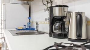 Uma cozinha com cafeteira, chaleira e fogão a gás.
