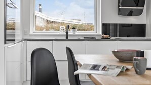 Una cocina moderna con armarios blancos, un grifo negro y una ventana con vistas al paisaje.