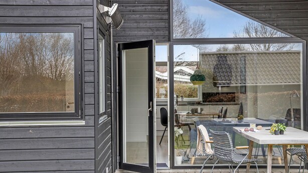 Una casa moderna con puerta corrediza de vidrio que da a un patio con mesa y sillas.