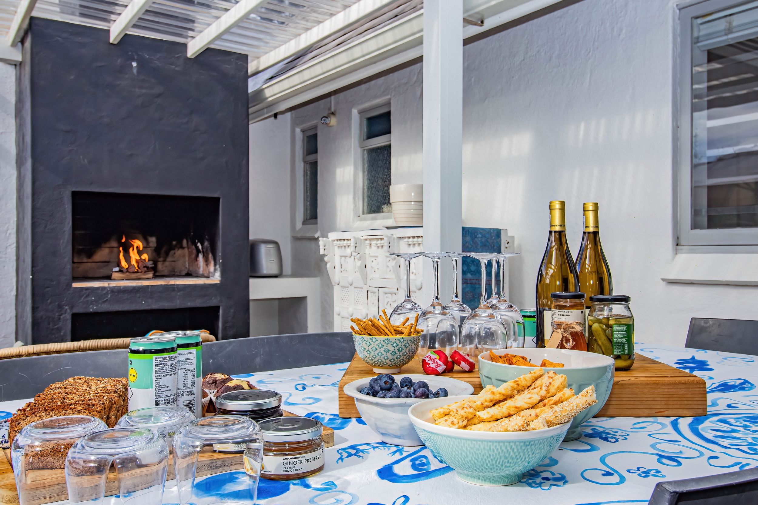 Une table dressée pour un repas, avec différents plats, des boissons et une cheminée en arrière-plan.