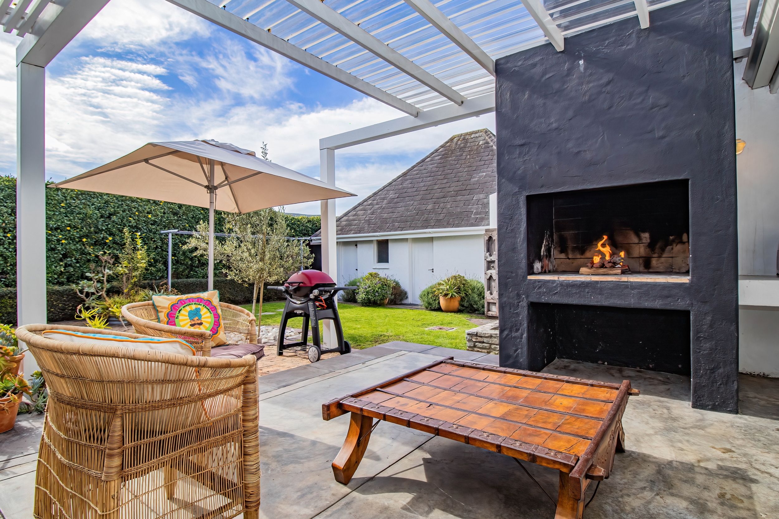 An outdoor patio with a grill, a fire pit, wicker furniture, and a pergola.