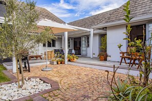 Un patio con suelo empedrado, mobiliario exterior y plantas en macetas.