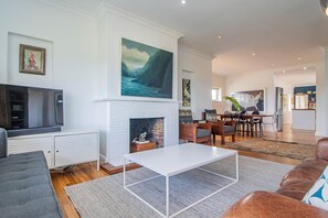 Una sala de estar moderna con chimenea, televisión y comedor.