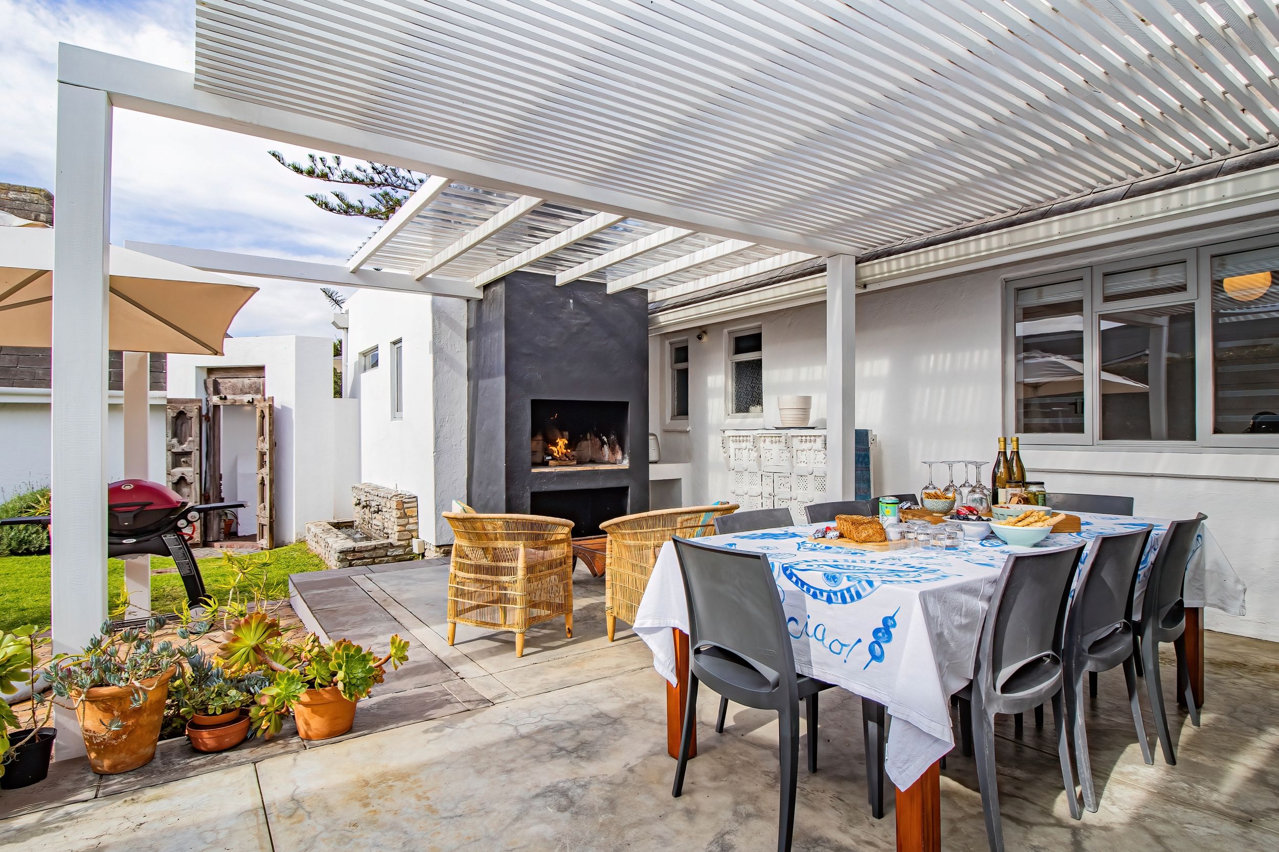 An outdoor patio area with a grill, seating, and a fireplace.