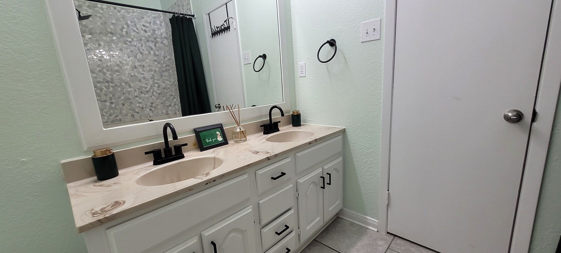 A bathroom with two sinks, a large mirror, and a door.