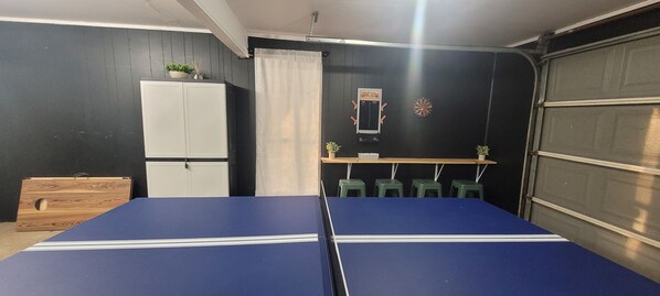 A room with a ping pong table, a white cabinet, a dartboard, and a sign indicating a game room. - Texas Evergreen Oasis WACO/Silos/Baylor: Pool, Spa, PingPong, Pets on 1/3 acre (Waco)