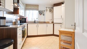 Una cocina moderna con armarios blancos, electrodomésticos de acero inoxidable y encimera de madera.