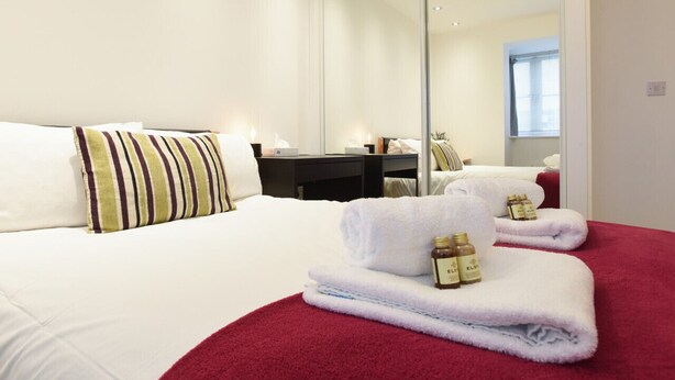 Una habitación de hotel con una cama, un escritorio, un espejo y toallas.