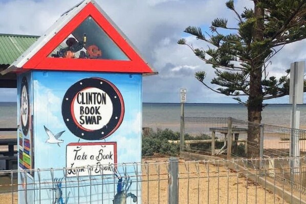 A book swap station with a sign that reads "CLINTON BOOK SWAP" and "Take a Book, Leave a Book". - Beachfront Gem | Cast a Line at 29 (Clinton)