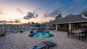 A backyard with a swimming pool, lounge chairs, and a dining area with outdoor seating.