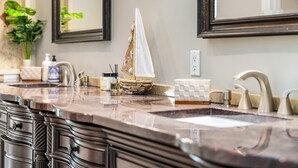 A bathroom with a large mirror, a sink with a modern faucet, and a decorative sailboat model.