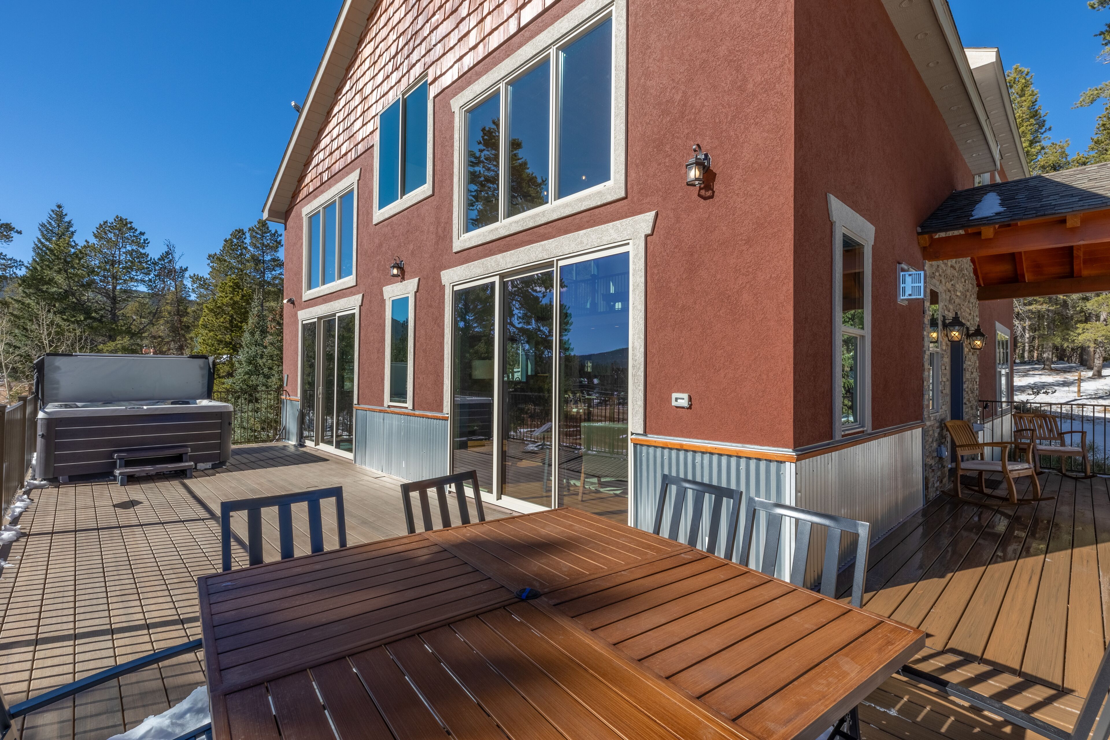 Et hus med en terrasse, grill og en stor skydedør.
