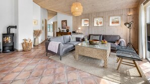 A cozy living room with a fireplace, a sofa, a coffee table, and a wicker bench.