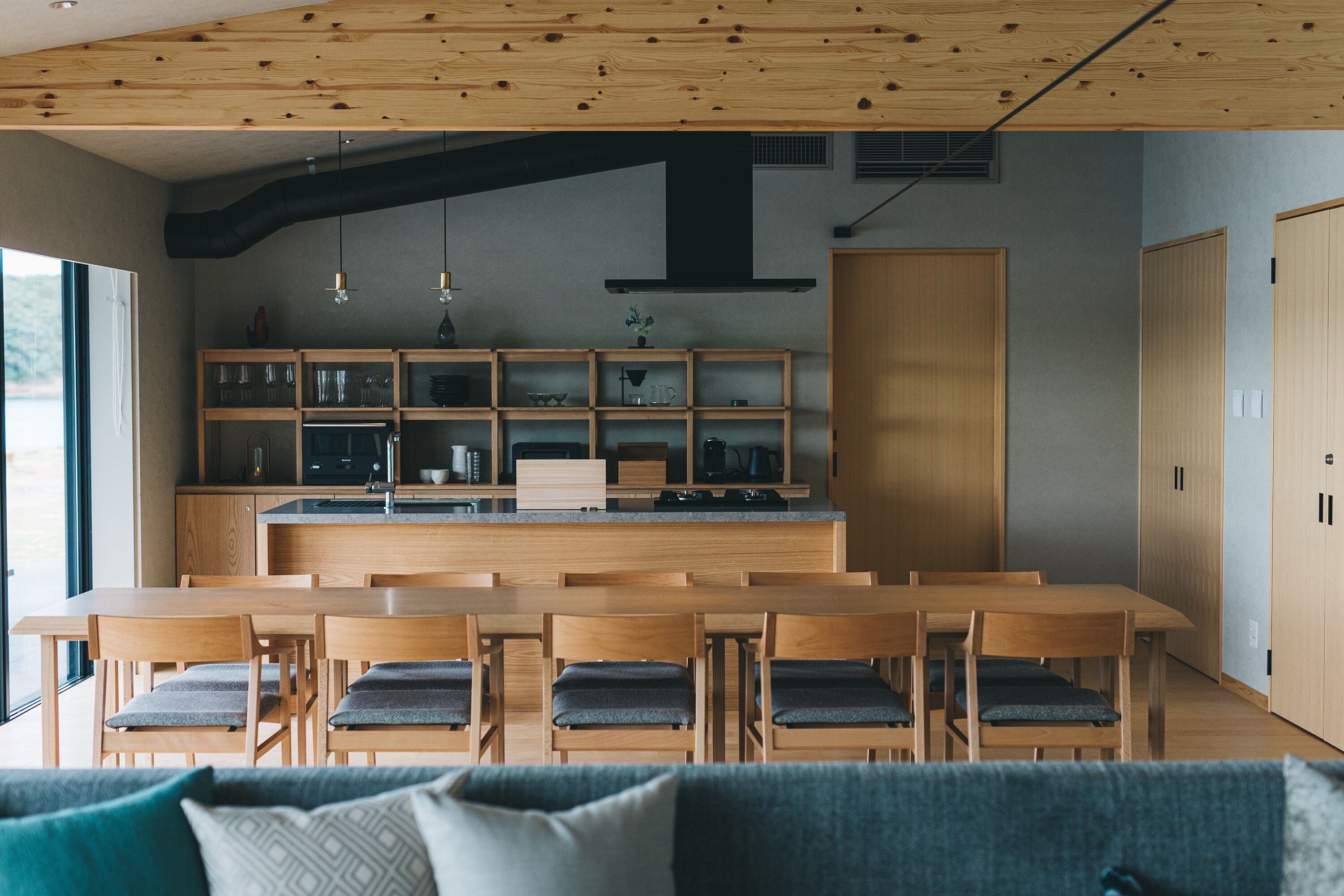 A modern kitchen with wooden cabinetry, a central island, and a dining area with wooden tables and chairs.