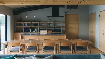 A modern kitchen with wooden cabinetry, a central island, and a dining area with wooden tables and chairs.