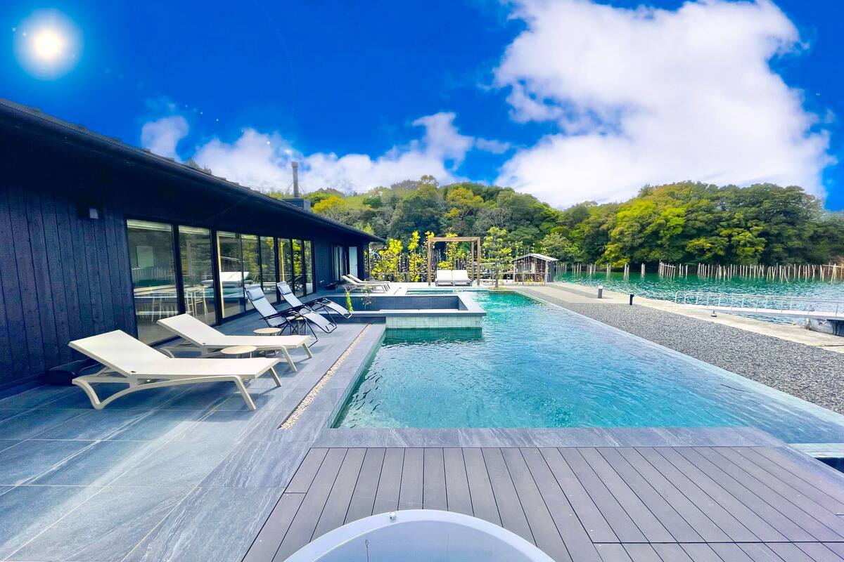 Un área de piscina moderna al aire libre con sillones de descanso y un jacuzzi.
