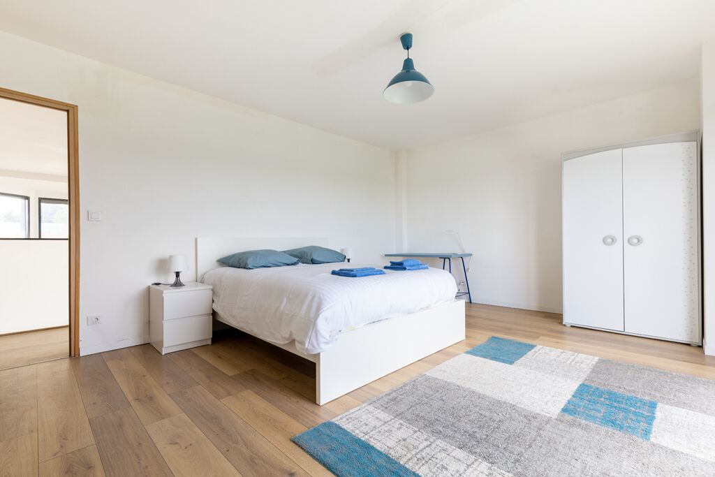 Un dormitorio con cama, mesita de noche, armario y una lámpara colgante azul.