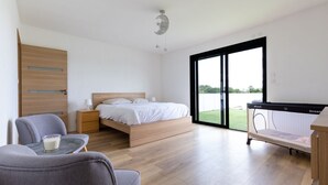 Een moderne slaapkamer met een bed, nachtkastje en een kleine tafel met een glas.
