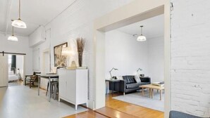 A modern interior with a kitchen, dining area, and living space, featuring white walls, wooden floors, and pendant lighting. - Rockland Central Loft, heart of downtown (Rockland)