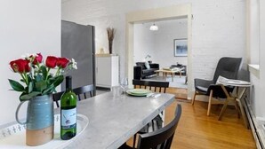 A modern living room with a dining table, chairs, a vase with flowers, and a wine bottle. - Rockland Central Loft, heart of downtown (Rockland)