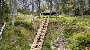 A wooden staircase leading to a house surrounded by trees. - Settlers Cottage, cute Maine home with water views (Cushing)