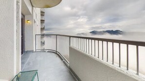 Een balkon met metalen hekwerk met uitzicht op een bergachtig landschap.