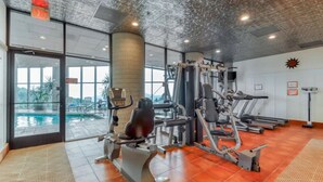 Een sportschool met fitnessapparatuur, een zwembad en grote ramen.