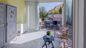 Een zonnig terras met een eettafel, stoelen en een potplant.