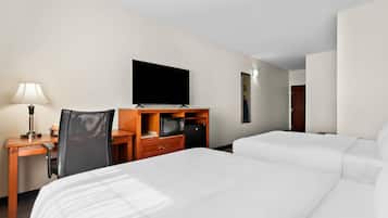 Una habitación de hotel con una cama, un escritorio con lámpara, un televisor y un microondas.