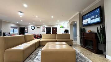 Un salón amplio con un sofá modular grande, un televisor de pantalla plana montado en la pared y una chimenea.