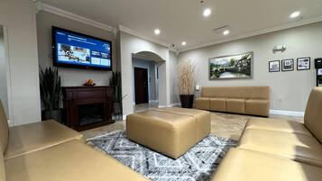 A modern living room with a fireplace, leather sofas, a flat-screen TV, and a painting on the wall.