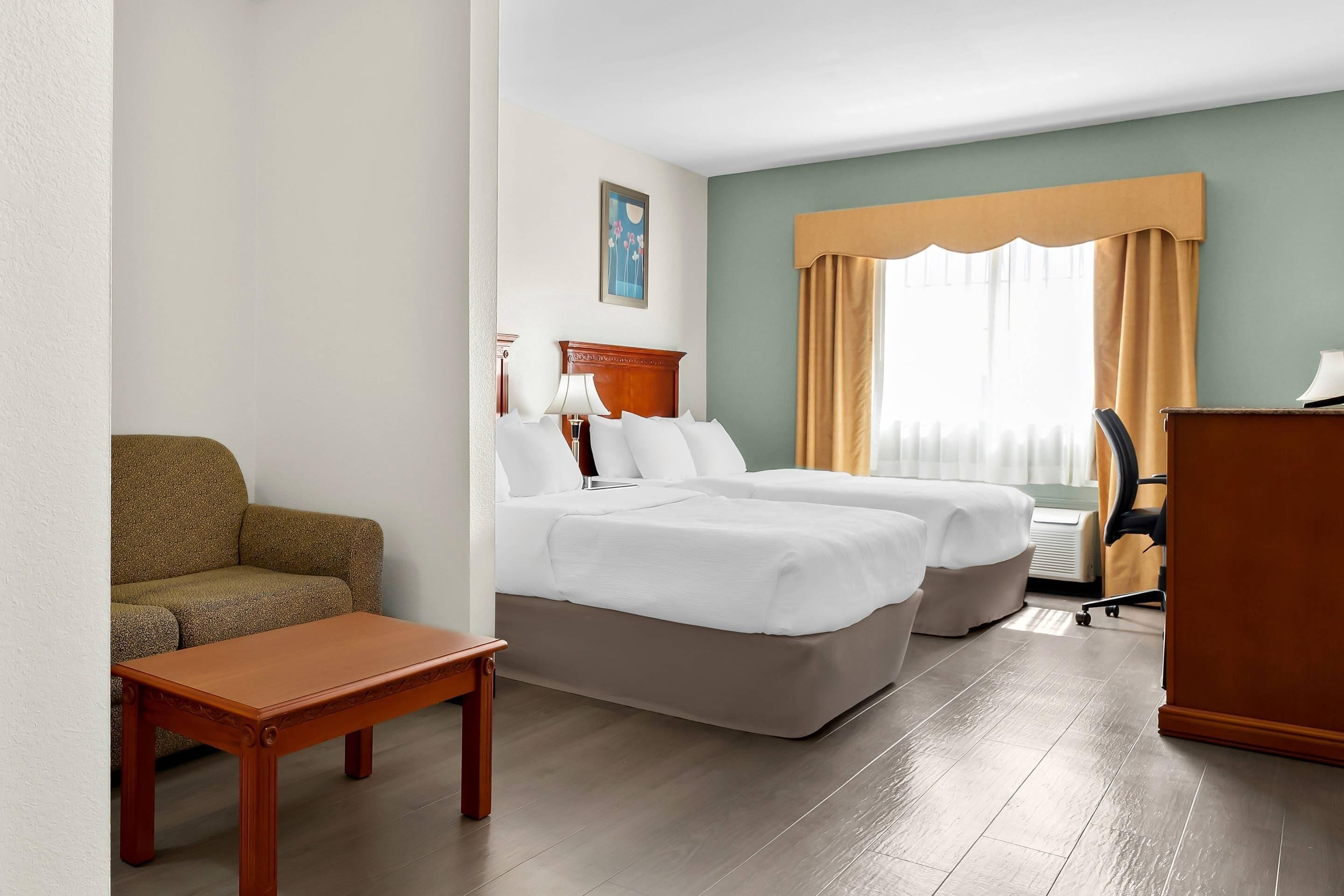 Une chambre d’hôtel avec un lit, un canapé, un bureau et une chaise.