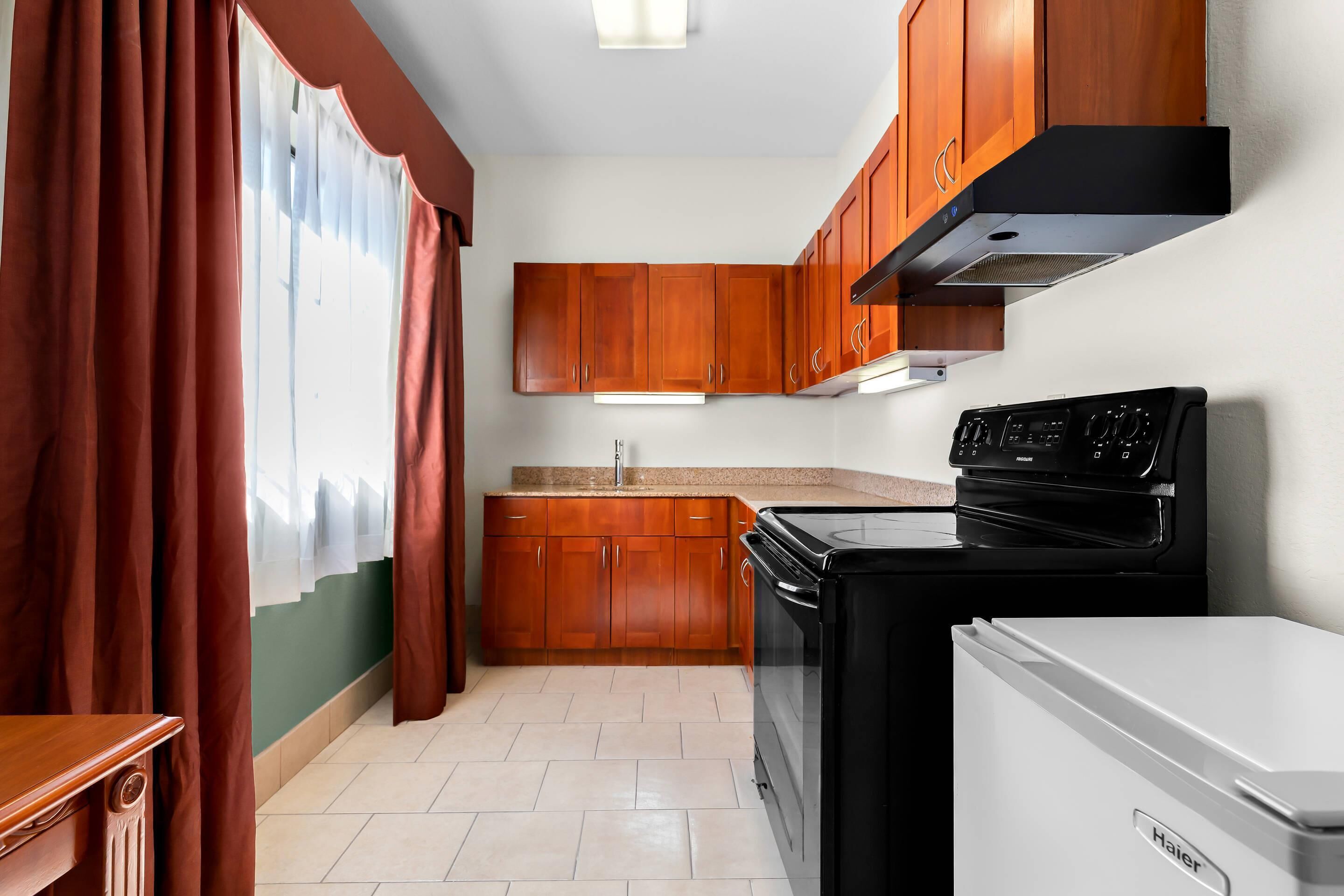 A kitchen with wooden cabinets, a black stove, and a white refrigerator.