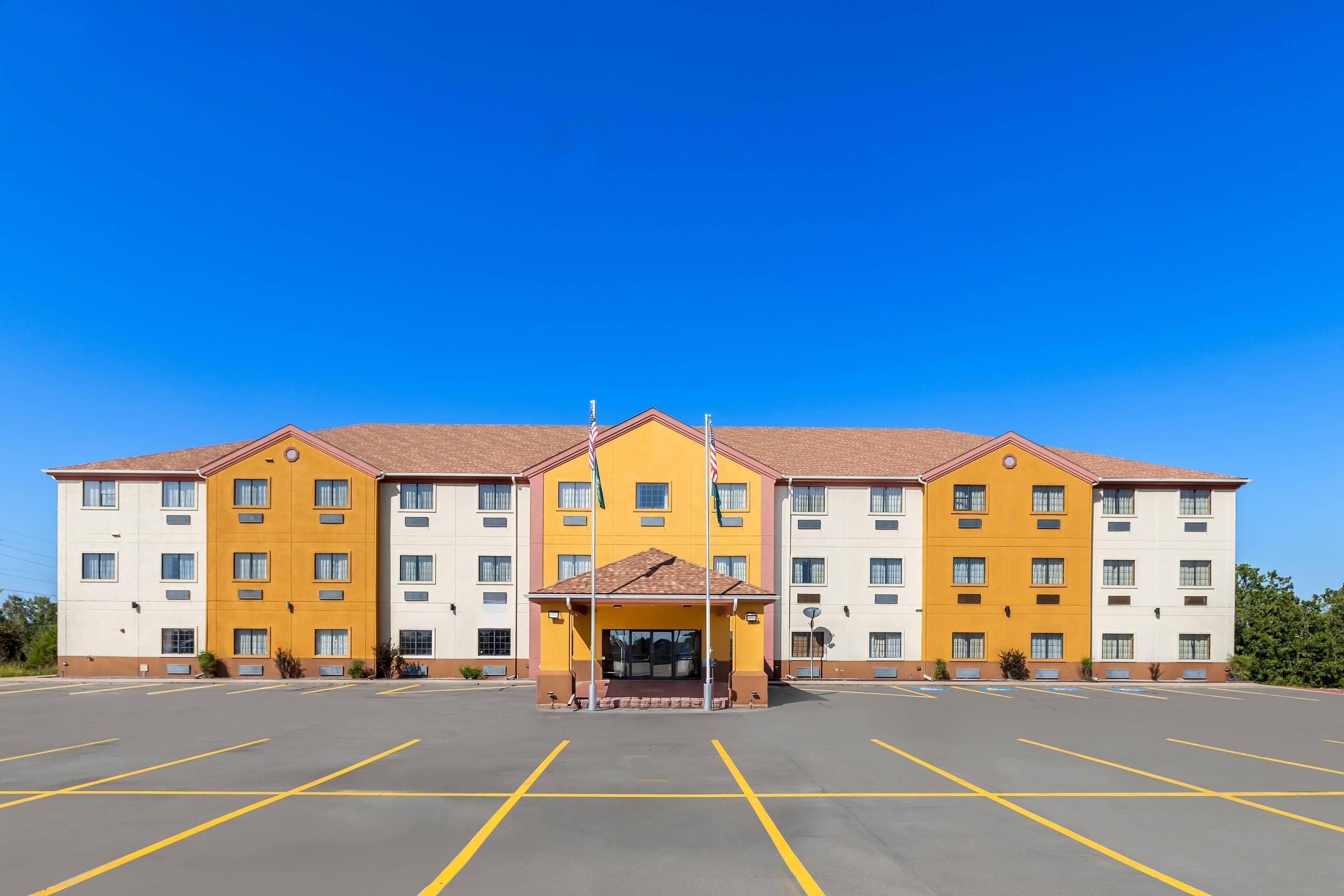 A multi-story hotel with a central entrance and a parking lot.