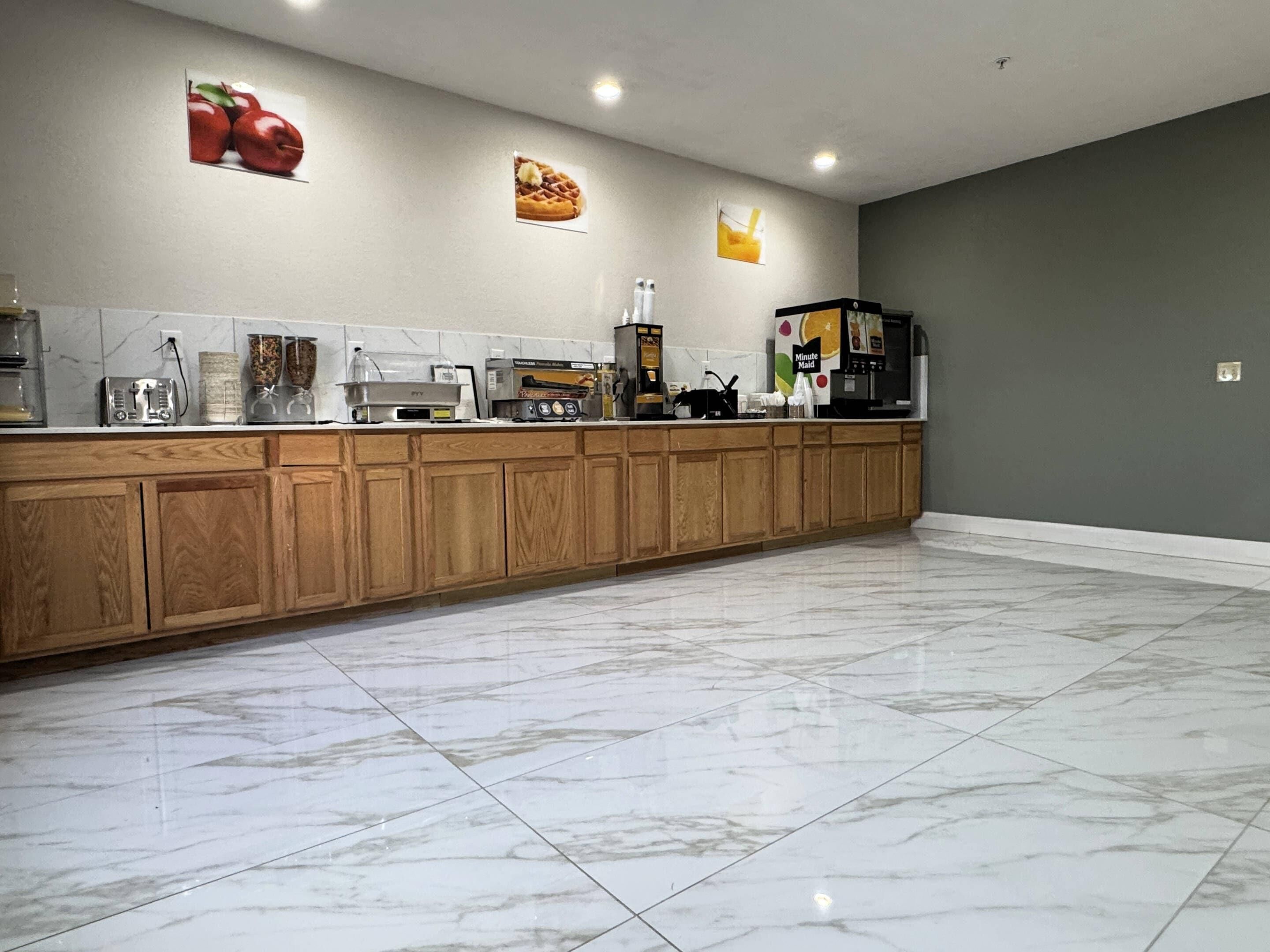 A modern kitchen with wooden cabinets, a marble floor, and various appliances.