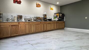 A modern kitchen with wooden cabinets, a marble floor, and various appliances.