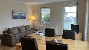 Ein modernes Wohnzimmer mit einer Couch, zwei Sesseln, einem Couchtisch, einer Lampe und einem Gemälde an der Wand.
