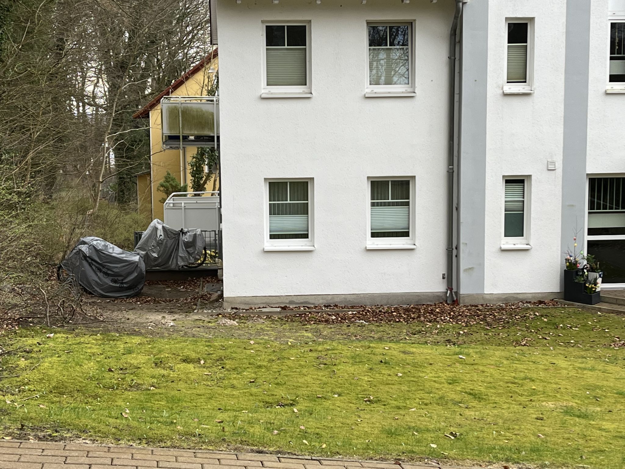 En hvid bygning med mange vinduer og et overdækket udendørs område.
