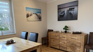Ein Essbereich mit Holztisch und Stühlen, einer Kommode mit Schubladen sowie zwei Bildern an der Wand.