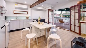 Una cocina moderna con armarios blancos, una mesa de comedor de madera y vistas a una terraza.