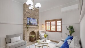 Una sala de estar con chimenea, un sofá, un sillón y una mesa de centro.