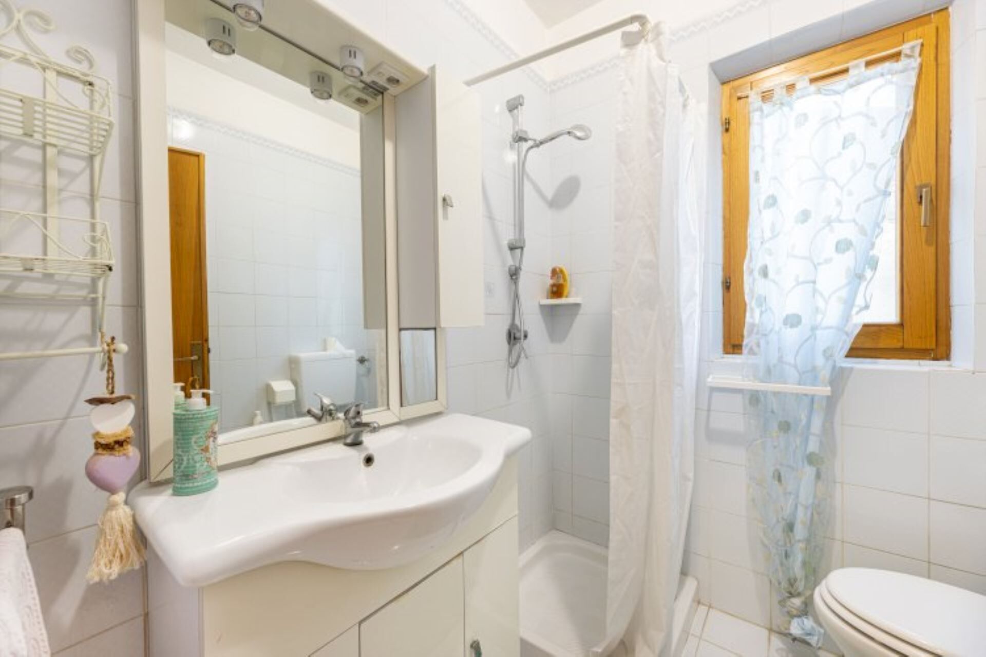 A bathroom with a white sink, a mirror, a shower, and a toilet.