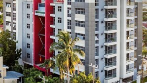 A multi-story building with balconies, a red accent wall, and a palm tree in the foreground. - Serenity suites (Kingston)
