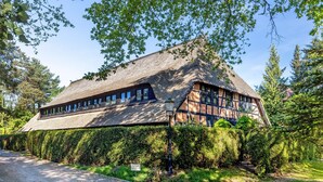 A traditional building with a thatched roof, surrounded by dense greenery and trees. - Apartment 'Wohnen Im Heidehaus' with Private Terrace and Wi-Fi (St. Dionys)